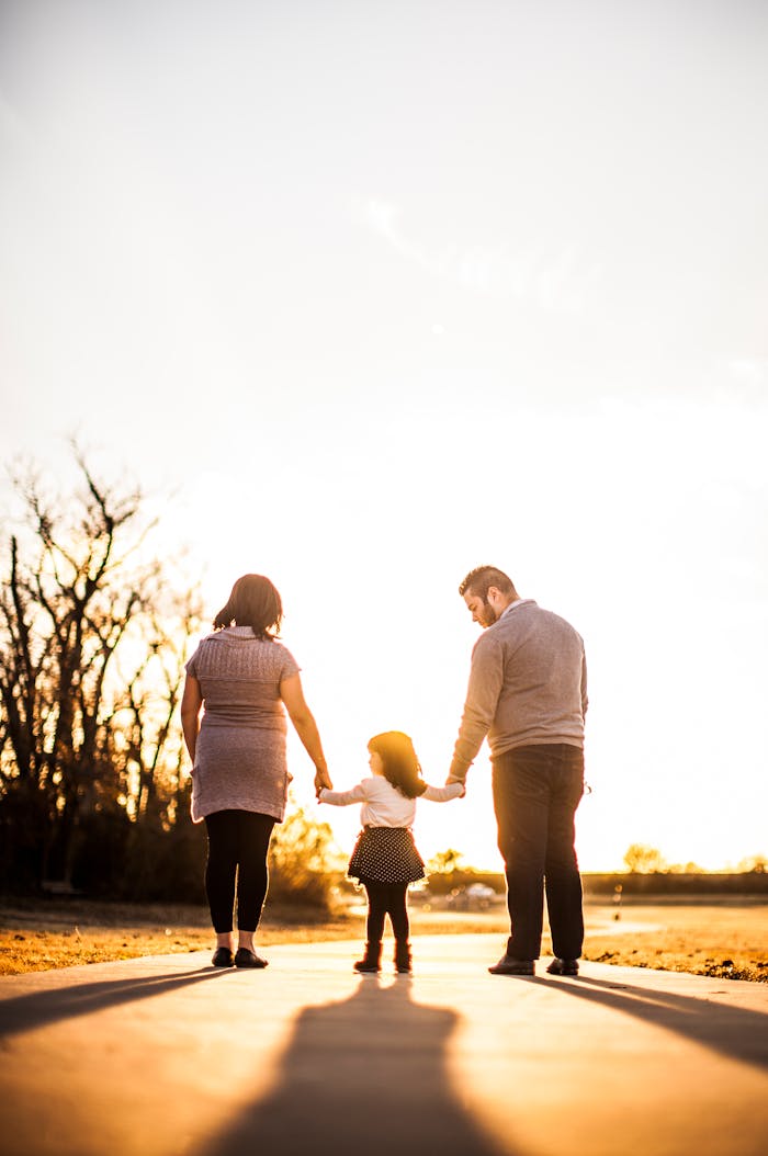 who-we-are-img A family of three walks hand in hand at sunset, enjoying togetherness and warmth.